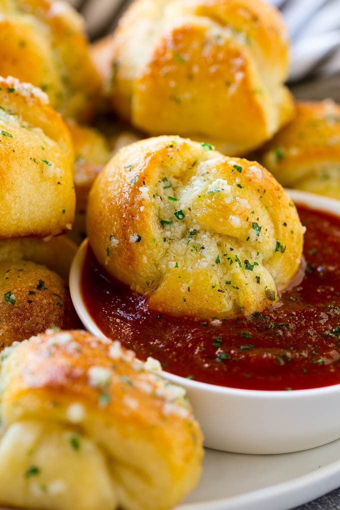 Garlic Knots Recipe | Garlic Rolls | Garlic Butter Rolls | Garlic Bread Recipe #garlic #garlicbread #garlicknots #breadsticks #bajap A garlic roll being dipped into marinara sauce for a delicious finishing touch.