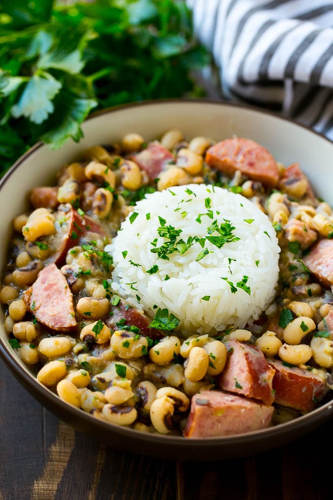 Slow Cooker Black Eyed Peas Recipe | Crock Pot Black Eyed Peas | Southern Black Eyed Peas | Black Eyed Peas with Ham | Black Eyed Peas with Sausage #blackeyedpeas #slowcooker #crockpot #sausage #newyears #dinner #bajap A bowl of slow cooker black eyed peas with a scoop of rice.