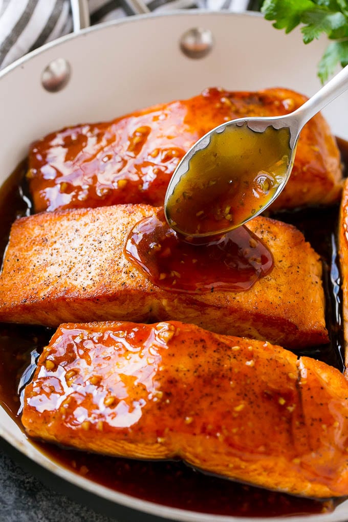 A spoon pouring sauce on top of salmon fillets.