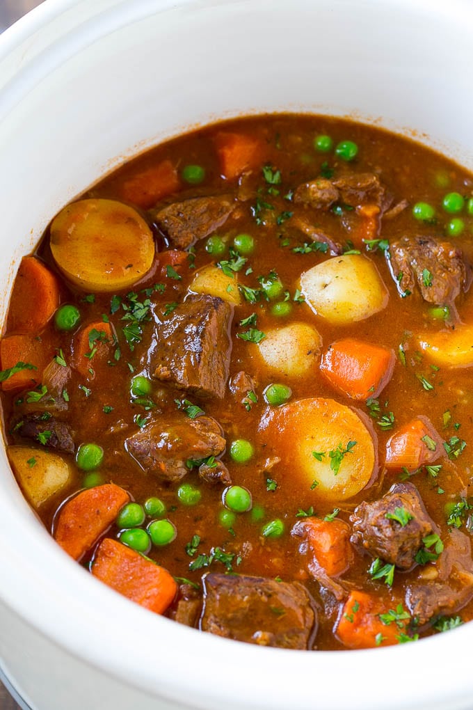 Slow Cooker Beef Stew Recipe | Beef and Potato Stew | Crock Pot Beef Stew | Easy Beef Stew #beef #beefstew #soup #slowcooker #crockpot #dinner #bajap A slow cooker full of beef stew that contains meat, potatoes, carrots and peas, all in a savory broth.