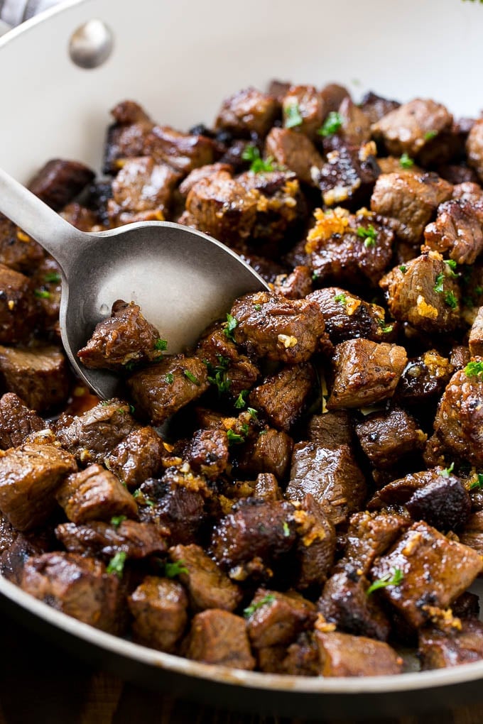 Steak Bites in Garlic Butter Recipe | Garlic Steak | Sirloin Steak Recipe | Steak Appetizer #steak #lowcarb #keto #bajap #dinner A pan of steak bites with a serving spoon.