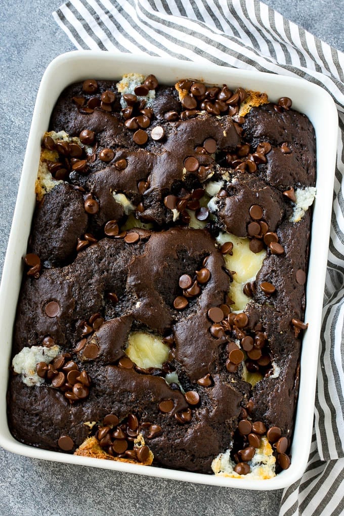 Earthquake Cake Recipe | Chocolate Cake Recipe | Chocolate Coconut Cake | Coconut Pecan Cake #cake #chocolate #coconut #pecans #dessert #chocolatecake #bajap A pan of earthquake cake topped with dollops of cream cheese and chocolate chips.