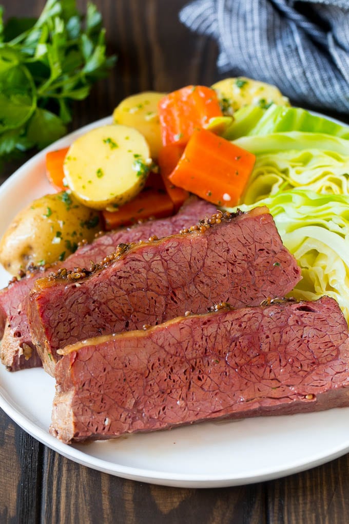 Slow Cooker Corned Beef Recipe | Crock Pot Corned Beef | Corned Beef and Cabbage #beef #cornedbeef #cabbage #potatoes #carrots #stpatricksday #irish #bajap Sliced slow cooker corned beef on a plate with carrots, potatoes and cabbage.