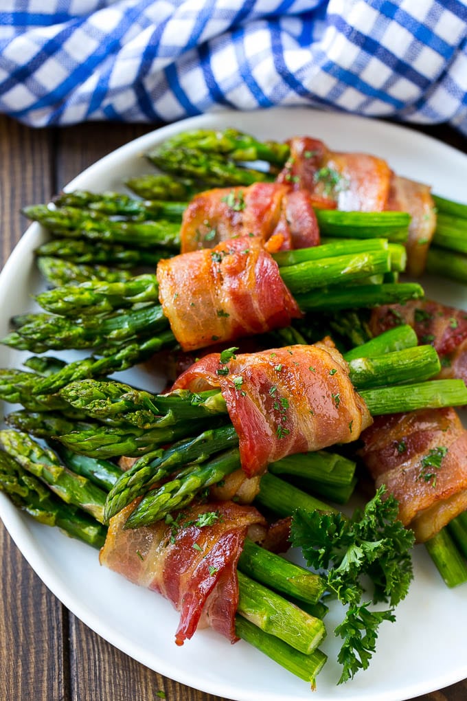 Bacon Wrapped Asparagus Recipe | Roasted Asparagus | Asparagus Side Dish #asparagus #bacon #sidedish #dinner #bajap A plate of bacon wrapped asparagus bundles garnished with parsley.