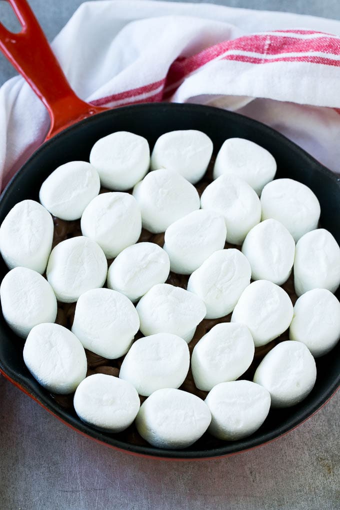 S'mores Dip Recipe | S'mores Skillet | Baked S'mores #smores #dip #chocolate #marshmallow #dessert #bajap A pan of chocolate chips topped with whole marshmallows.