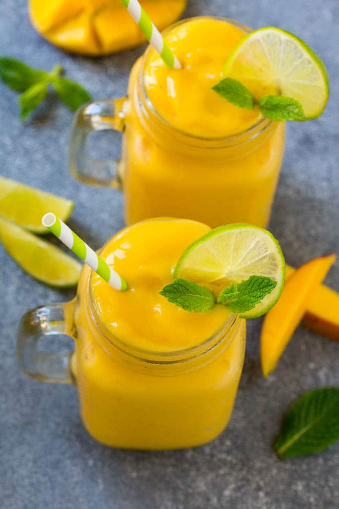 Mango Smoothie Recipe | Mango Recipe | Healthy Smoothie #mango #smoothie #drink #bajap Two jars full of mango smoothie, garnished with lime slices and fresh mint.