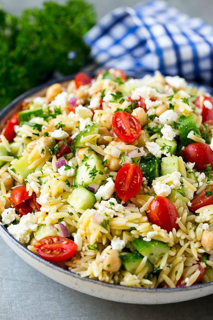 Orzo Salad Recipe | Orzo Pasta Salad | Greek Orzo Salad | Mediterranean Orzo Salad #pastasalad #orzo #greekfood #salad #bajap Orzo salad in a serving bowl with tomatoes, cucumbers and chickpeas.