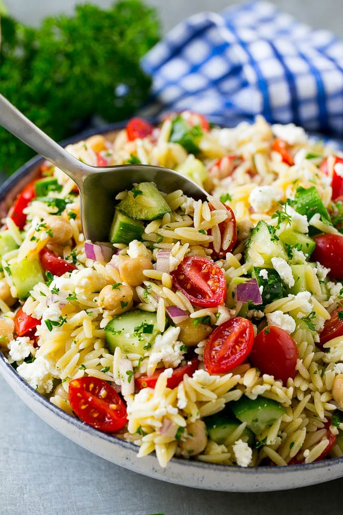 Orzo Salad Recipe | Orzo Pasta Salad | Greek Orzo Salad | Mediterranean Orzo Salad #pastasalad #orzo #greekfood #salad #bajap Orzo pasta salad with a serving spoon in the bowl.