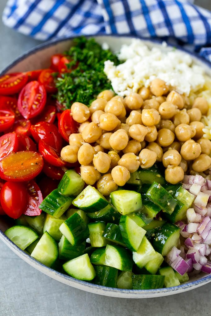 Orzo Salad Recipe | Orzo Pasta Salad | Greek Orzo Salad | Mediterranean Orzo Salad #pastasalad #orzo #greekfood #salad #bajap A bowl of orzo pasta, tomatoes, cucumbers, red onions, chickpeas and feta cheese topped with dressing.