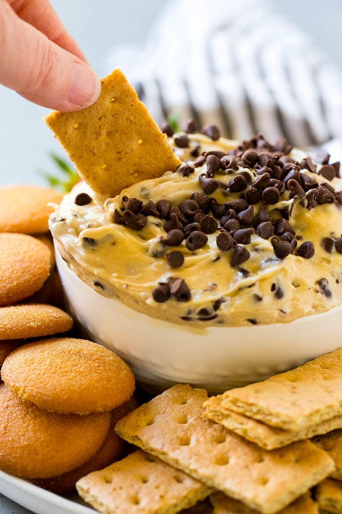 Cookie Dough Dip Recipe | Edible Cookie Dough | Chocolate Chip Cookie Dip #cookies #dip #cookiedough #dessert #snack #bajap A graham cracker dipping into a bowl of cookie dough dip.