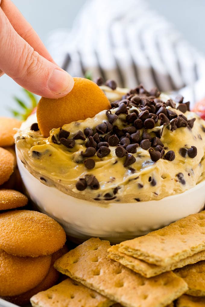 Cookie Dough Dip Recipe | Edible Cookie Dough | Chocolate Chip Cookie Dip #cookies #dip #cookiedough #dessert #snack #bajap A cookie scooping into a bowl of dip.