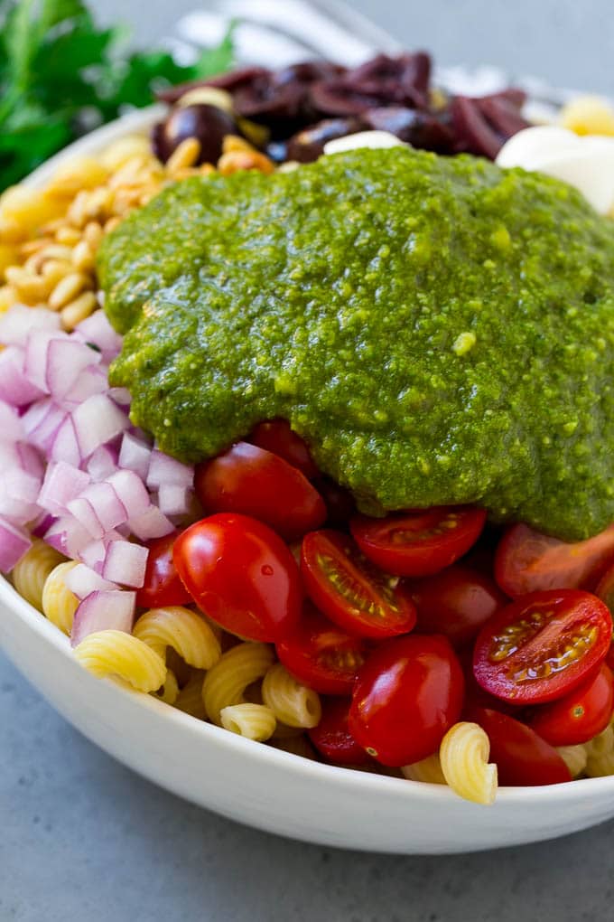 Pesto Pasta Salad | Italian Pasta Salad | Easy Pasta Salad #pasta #salad #pesto #olives #tomatoes #bajap Vegetables and corkscrew pasta topped with fresh pesto.