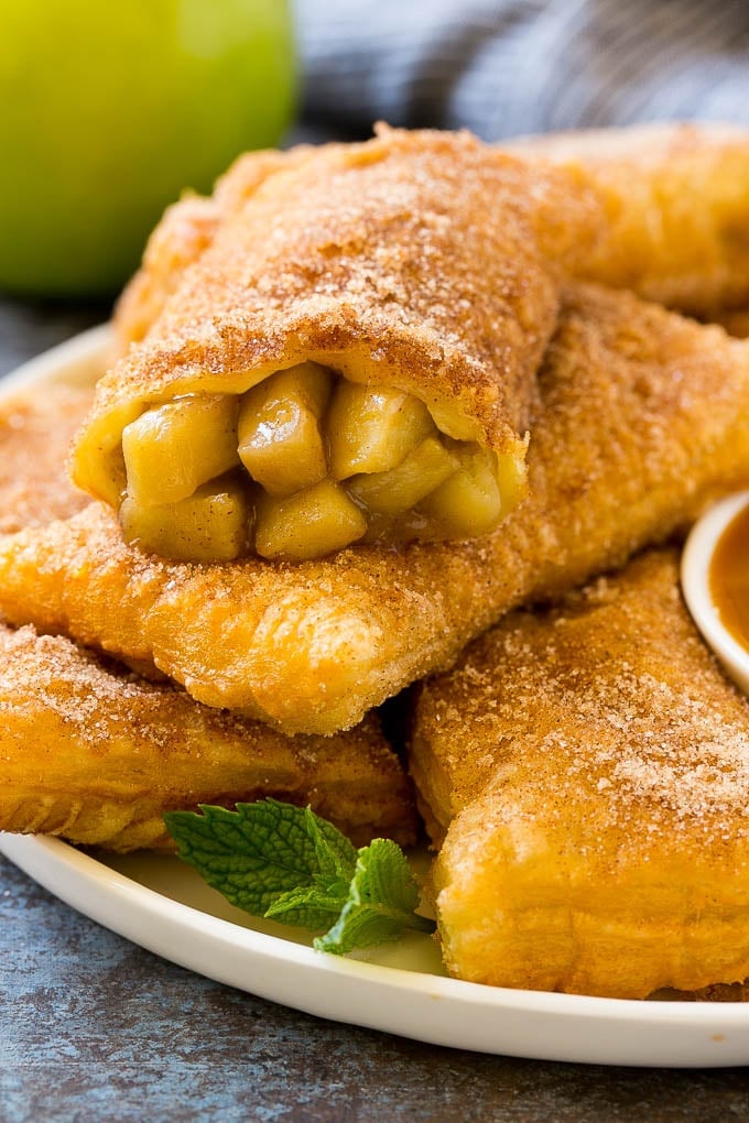 Fried Apple Pies Recipe | McDonald's Copycat Recipe | Apple Pie | Apple Hand Pies #pie #apples #applepie #dessert #snack #bajap Fried apple pies on a plate served with caramel sauce and topped with cinnamon sugar.