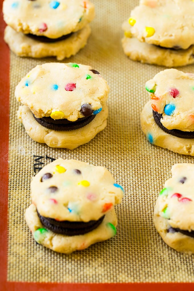 Oreo Stuffed Cookies Recipe | M&M's cookies | Stuffed Cookies #cookies #chocolate #oreos #dessert #baking #bajap Cookie dough sandwiched around Oreos on a baking sheet.