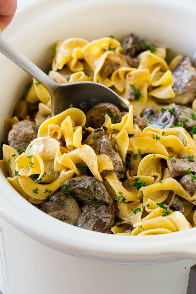 Slow Cooker Beef Stroganoff Recipe | Crock Pot Beef Stroganoff | Beef Recipe #slowcooker #crockpot #beef #mushrooms #pasta #dinner #bajap A crock pot of beef stroganoff with a serving spoon in it.