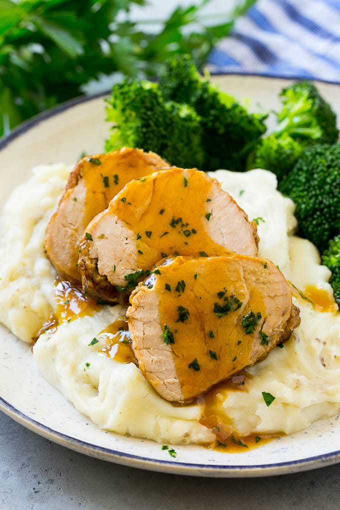 Slow Cooker Pork Tenderloin Recipe | Crock Pot Pork Tenderloin | Easy Pork Tenderloin #slowcooker #crockpot #pork #dinner #bajap Sliced slow cooker pork tenderloin served over mashed potatoes with broccoli.