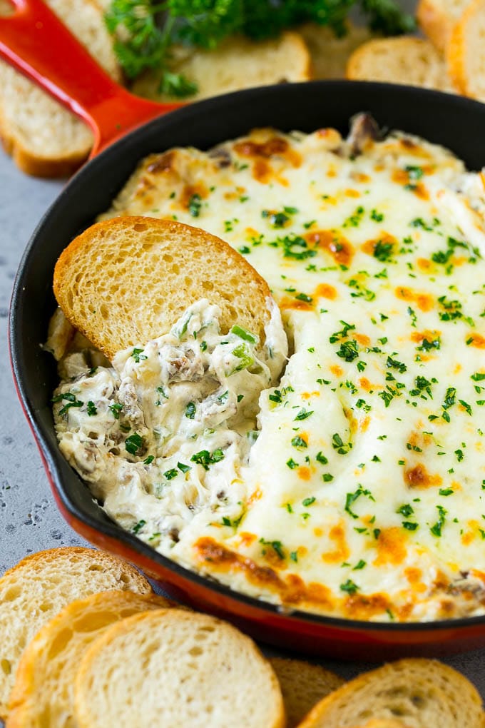 Philly Cheesesteak Dip Recipe | Cheesy Dip | Baked Cheese Dip #steak #dip #appetizer #cheese #bajap Philly cheesesteak dip with a baguette piece scooping some dip out.