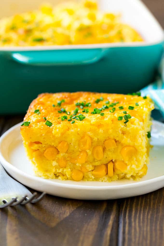 Corn Pudding Recipe | Corn Casserole | Corn Side Dish #corn #pudding #casserole #sidedish #thanksgiving #dinner #bajap A serving of corn pudding on a plate, garnished with chives.