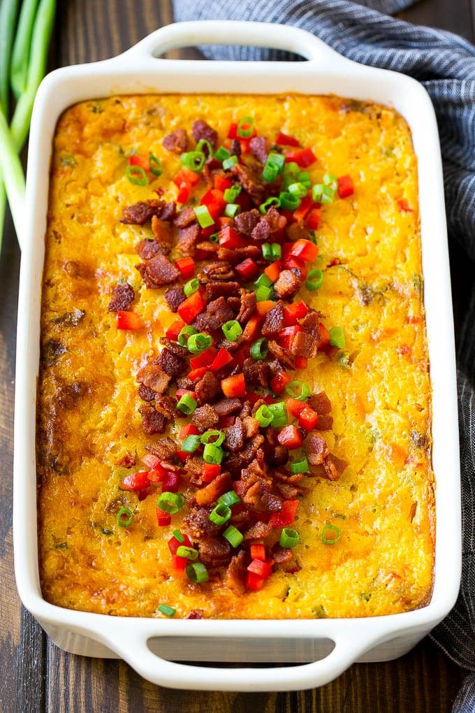 Loaded Corn Casserole Recipe | Easy Corn Casserole | Bacon Corn Casserole | Corn Pudding #corn #casserole #bacon #cheese #sidedish #thanksgiving #dinner #bajap A casserole of loaded corn casserole topped with bacon, red peppers and green onions.