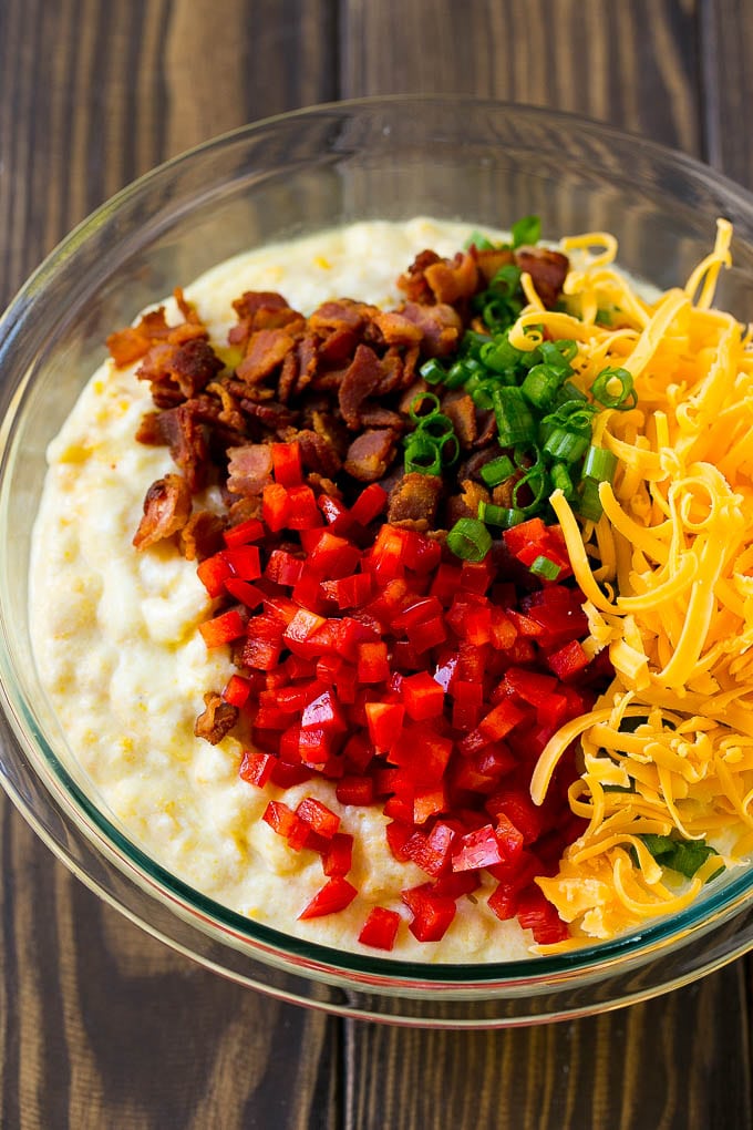 Loaded Corn Casserole Recipe | Easy Corn Casserole | Bacon Corn Casserole | Corn Pudding #corn #casserole #bacon #cheese #sidedish #thanksgiving #dinner #bajap A bowl of batter with red pepper, green onions, cheddar cheese and bacon.