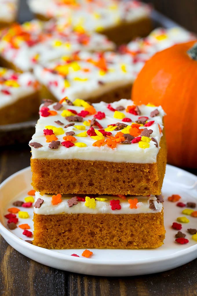 Pumpkin Bars Recipe | Pumpkin Cake | Pumpkin Dessert #pumpkin #fall #dessert #bajap #thanksgiving A stack of pumpkin bars topped with frosting and sprinkles.