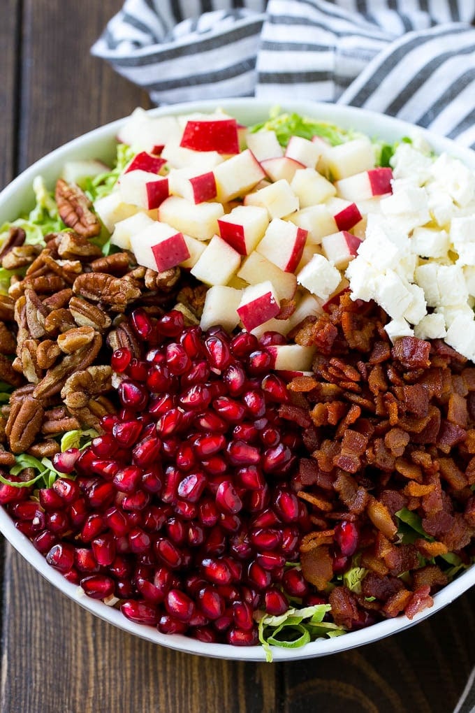 Brussels Sprout Salad Recipe | Shredded Brussels Sprouts Salad | Fall Salad #salad #brusselssprouts #bacon #thanksgiving #pomegranate #apple #dinner #bajap Shredded brussels sprouts topped with pomegranate seeds, bacon, feta cheese and apples.