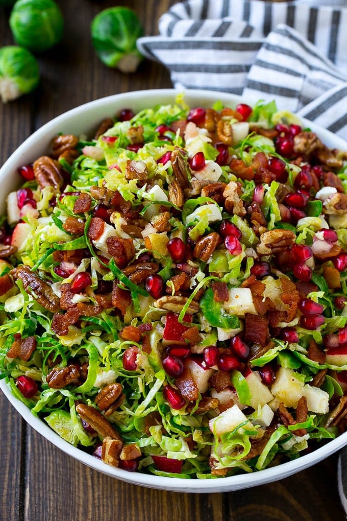 Brussels Sprout Salad Recipe | Shredded Brussels Sprouts Salad | Fall Salad #salad #brusselssprouts #bacon #thanksgiving #pomegranate #apple #dinner #bajap A bowl of salad made with pomegranate, bacon and apples.