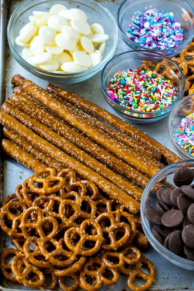 Chocolate Covered Pretzels Recipe | Sprinkle Pretzels | No Bake Dessert #pretzels #chocolate #christmas #sprinkles #candy #bajap Ingredients including candy melts and sprinkles on a sheet pan.