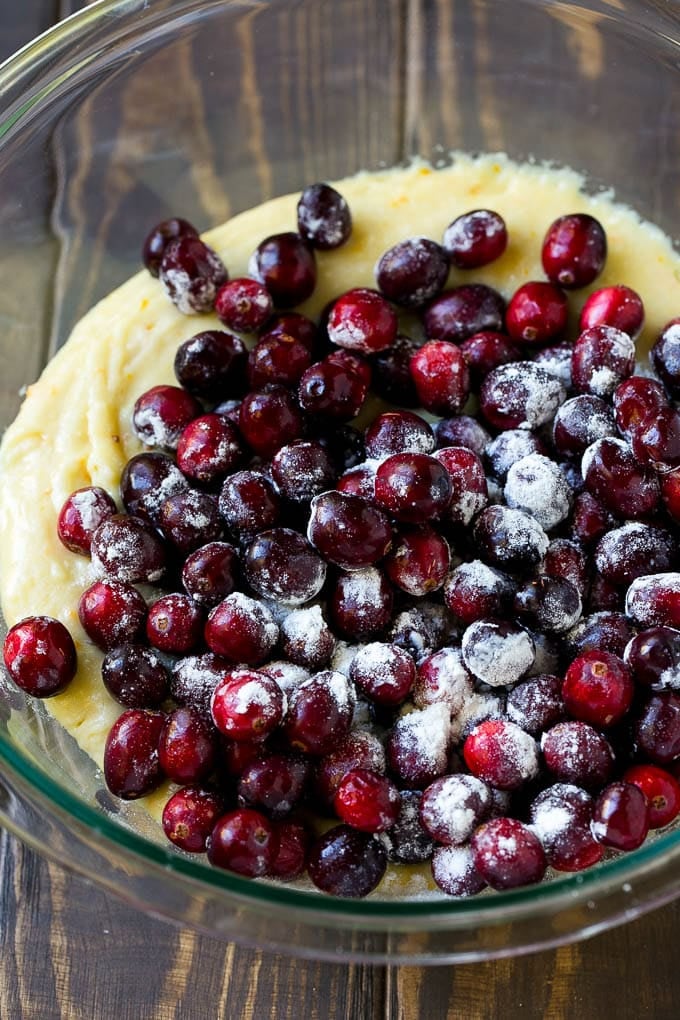 Cranberry Bread Recipe | Cranberry Loaf | Cranberry Orange Bread #cranberry #bread #baking #dessert #fall #bajap Orange batter topped with a pile of fresh cranberries in a mixing bowl.