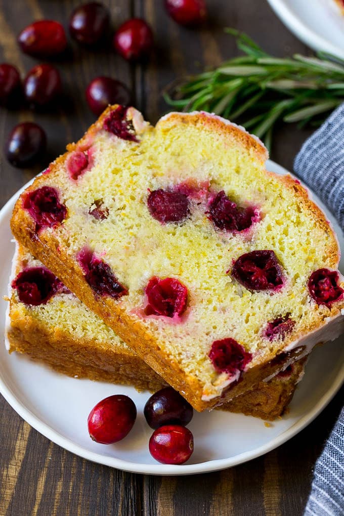 Cranberry Bread Recipe | Cranberry Loaf | Cranberry Orange Bread #cranberry #bread #baking #dessert #fall #bajap A plate with two slices of cranberry bread and fresh cranberries for garnish.
