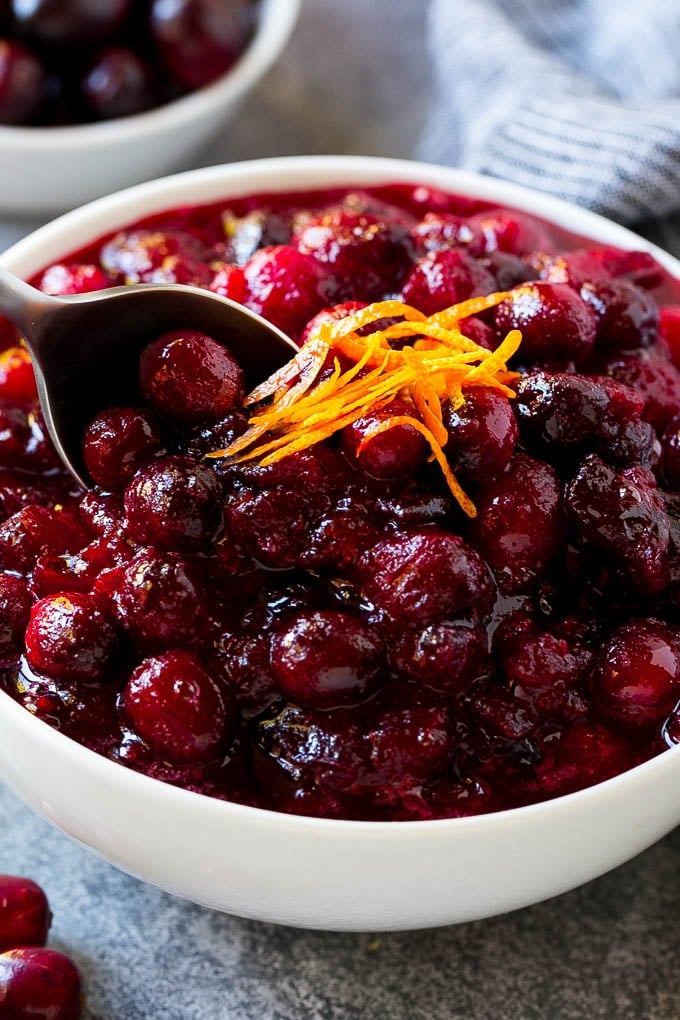 Cranberry Orange Sauce Recipe | Homemade Cranberry Sauce | Fresh Cranberry Sauce #cranberry #orange #fall #thanksgiving #sauce #dinner #bajap A serving spoon in a bowl of cranberry orange sauce.