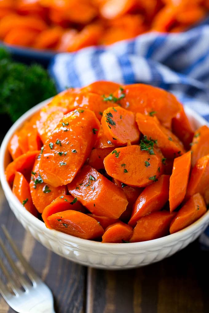 Glazed Carrots Recipe | Brown Sugar Carrots | Carrot Side Dish #carrots #brownsugar #sidedish #glutenfree #thanksgiving #fall #dinner #bajap A bowl of glazed carrots topped with parsley.