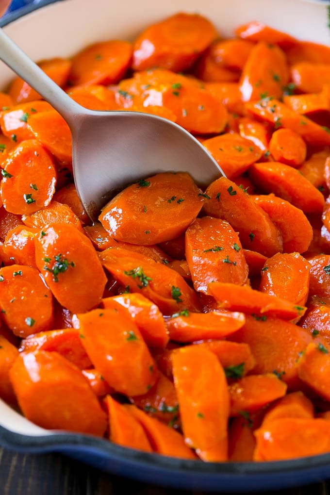 Glazed Carrots Recipe | Brown Sugar Carrots | Carrot Side Dish #carrots #brownsugar #sidedish #glutenfree #thanksgiving #fall #dinner #bajap Glazed carrots in a skillet with a serving spoon.
