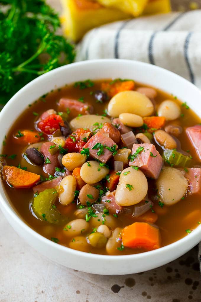 Ham and Bean Soup Recipe | Slow Cooker Ham and Bean Soup | Crockpot Ham and Bean Soup | Leftover Ham Recipe #ham #beans #soup #slowcooker #crockpot #dinner #bajap A bowl of ham and bean soup made with dried beans, ham and vegetables, then topped with fresh parsley.