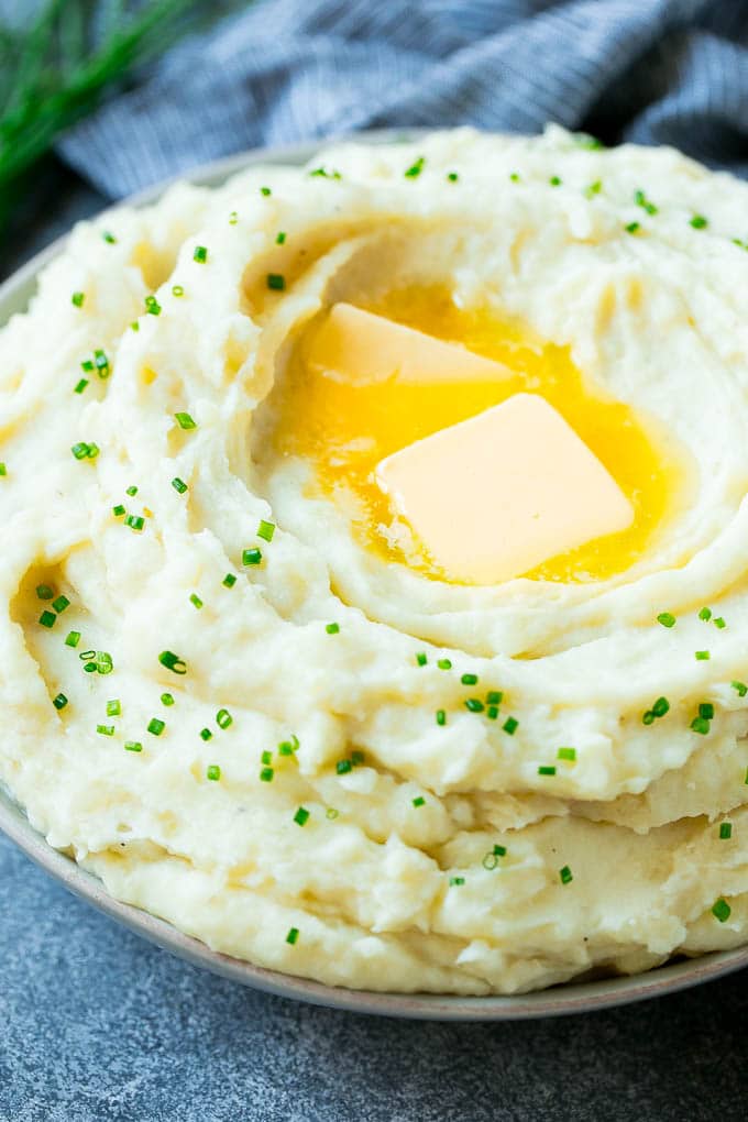 Instant Pot Mashed Potatoes Recipe | Pressure Cooker Mashed Potatoes | Easy Mashed Potatoes #potatoes #sidedish #instantpot #thanksgiving #dinner #bajap A bowl of fluffy Instant Pot mashed potatoes topped with pats of butter and sliced chives.