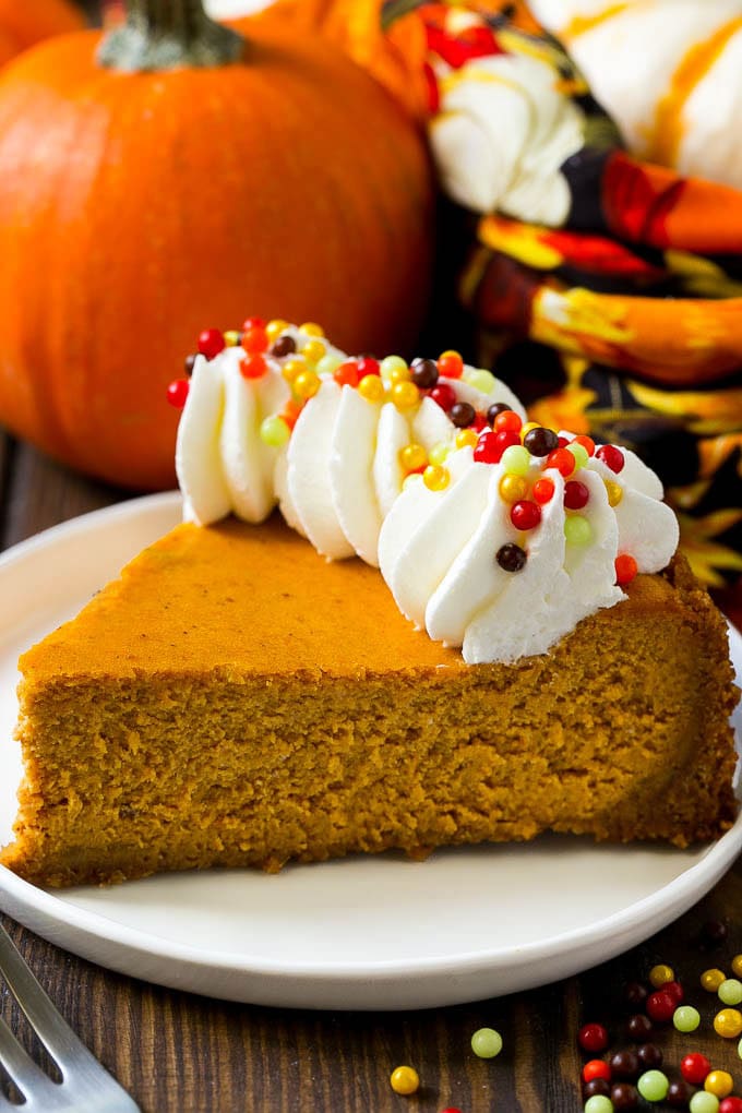Pumpkin Cheesecake Recipe | Pumpkin Pie Cheesecake | Pumpkin Dessert #pumpkin #thanksgiving #dessert #cheesecake #fall #bajap A slice of pumpkin cheesecake on a graham cracker crust, topped with whipped cream and sprinkles.