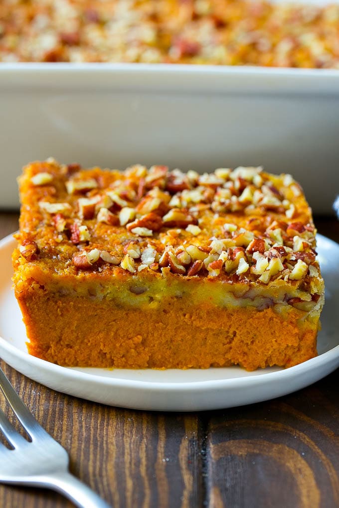 Pumpkin Dump Cake Recipe | Pumpkin Cake | Pumpkin Pie Cake #pumpkin #cake #pecans #fall #thanksgiving #dessert #bajap A slice of pumpkin dump cake topped with pecans.