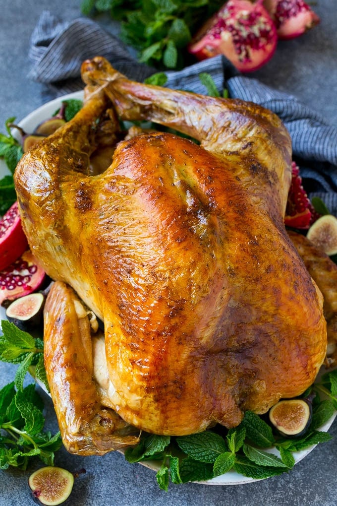 Roast Turkey Recipe | Thanksgiving Turkey | Holiday Turkey | Baked Turkey #turkey #thanksgiving #christmas #dinner #glutenfree #bajap A Thanksgiving roast turkey on a serving platter garnished with herbs, pomegranate and figs.