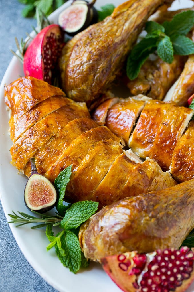 Roast Turkey Recipe | Thanksgiving Turkey | Holiday Turkey | Baked Turkey #turkey #thanksgiving #christmas #dinner #glutenfree #bajap Sliced roast turkey on a serving platter with rosemary, pomegranate and figs.