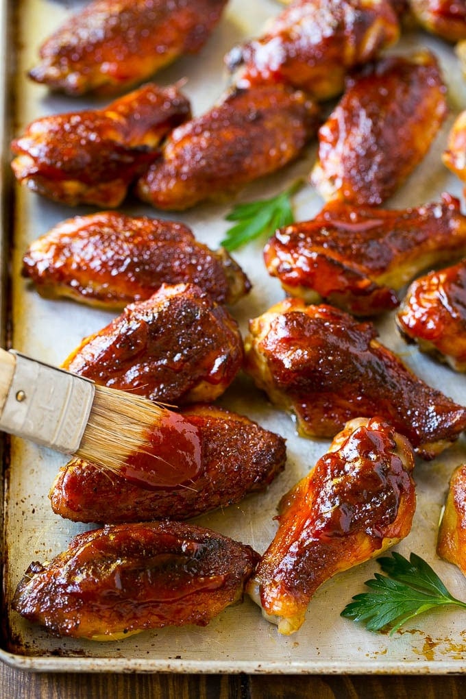 Smoked Chicken Wings | Barbecue Chicken Wings | BBQ Chicken Wings #chicken #wings #bbq #barbecue #appetizer #dinner #bajap BBQ sauce brushed onto a sheet pan of smoked chicken wings.