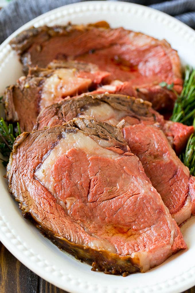 Smoked Prime Rib Recipe | Easy Prime Rib | Smoked Beef | Holiday Prime Rib #primerib #beef #smoker #dinner #bajap #christmas #thanksgiving #lowcarb #keto Slices of beef garnished with fresh herbs.