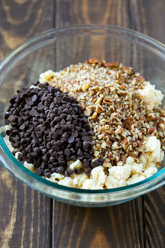 Snowball Cookies Recipe | Mexican Wedding Cookies | Russian Tea Cakes #cookies #pecan #chocolate #baking #dessert #christmas #bajap A bowl of dough topped with miniature chocolate chips and chopped pecans.