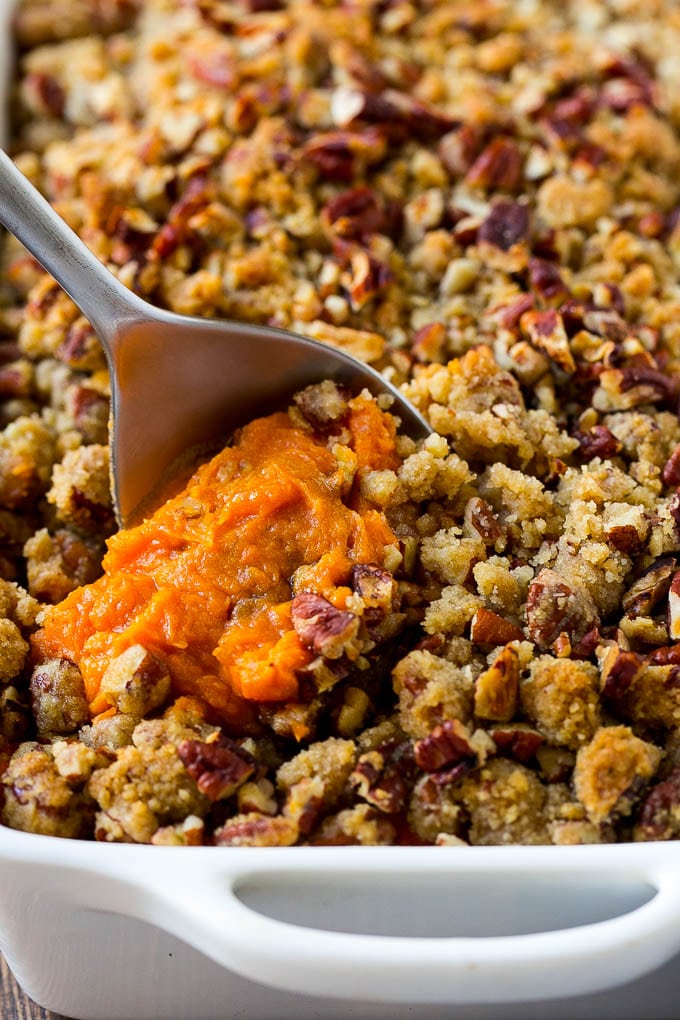 Sweet Potato Casserole with Pecans Recipe | Sweet Potato Casserole | Sweet Potato Side Dish #sweetpotatoes #thanksgiving #pecans #casserole #sidedish #holiday #fall #bajap A dish of sweet potato casserole with pecans with a serving spoon in it.