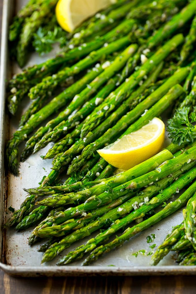 Roasted Asparagus Recipe | Baked Asparagus | Asparagus Side Dish #asparagus #garlic #sidedish #keto #lowcarb #dinner #bajap Roasted asparagus on a sheet pan, topped with chopped parsley and garnished with lemon wedges.