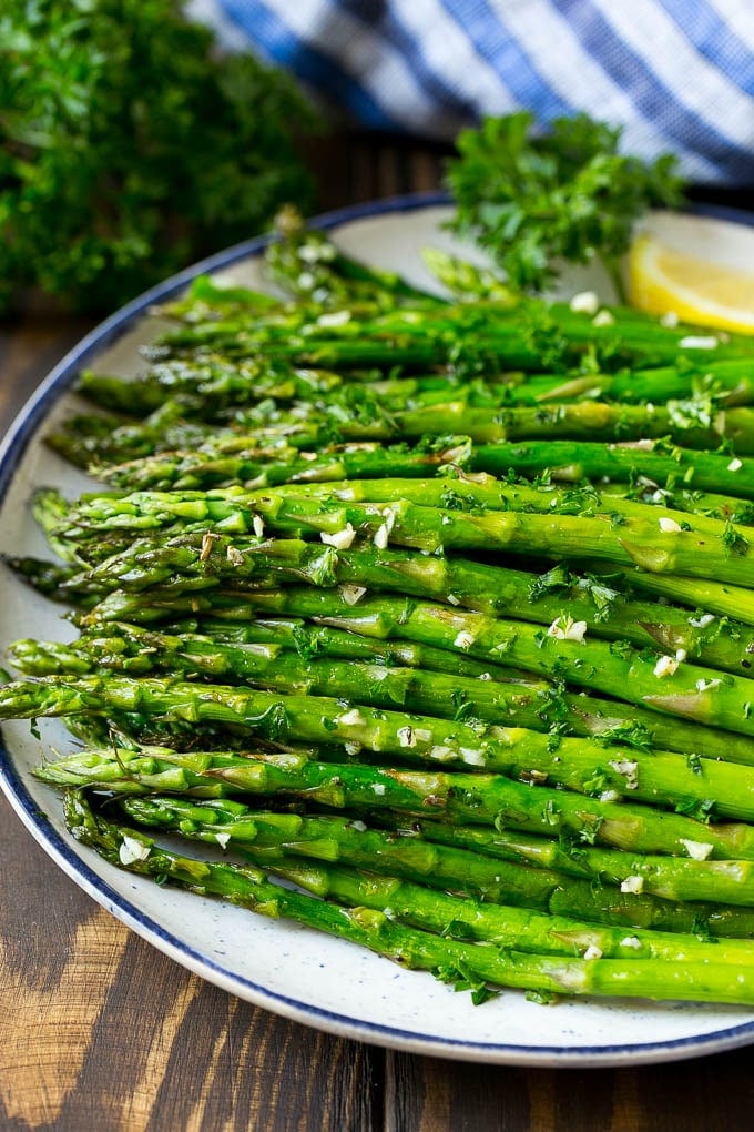 Roasted Asparagus Recipe | Baked Asparagus | Asparagus Side Dish #asparagus #garlic #sidedish #keto #lowcarb #dinner #bajap A serving plate of roasted asparagus topped with chopped parsley.