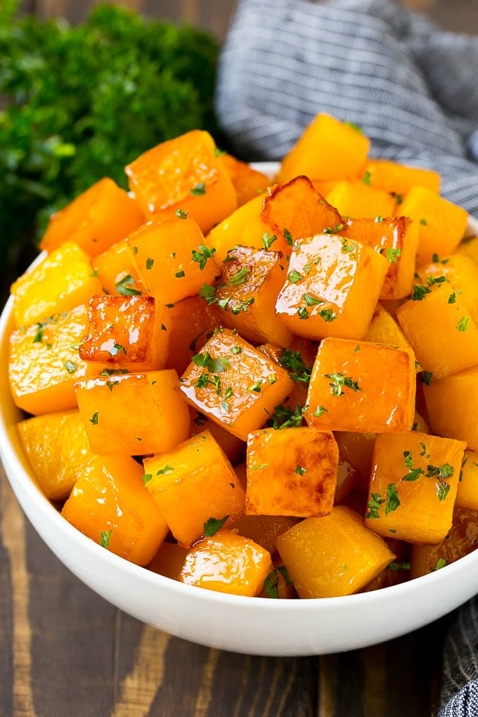 Roasted Butternut Squash Recipe | Baked Butternut Squash | Butternut Squash Side Dish #butternutsquash #squash #fall #vegetarian #dinner #bajap A bowl of roasted butternut squash made with brown sugar and maple syrup, then garnished with chopped parsley.