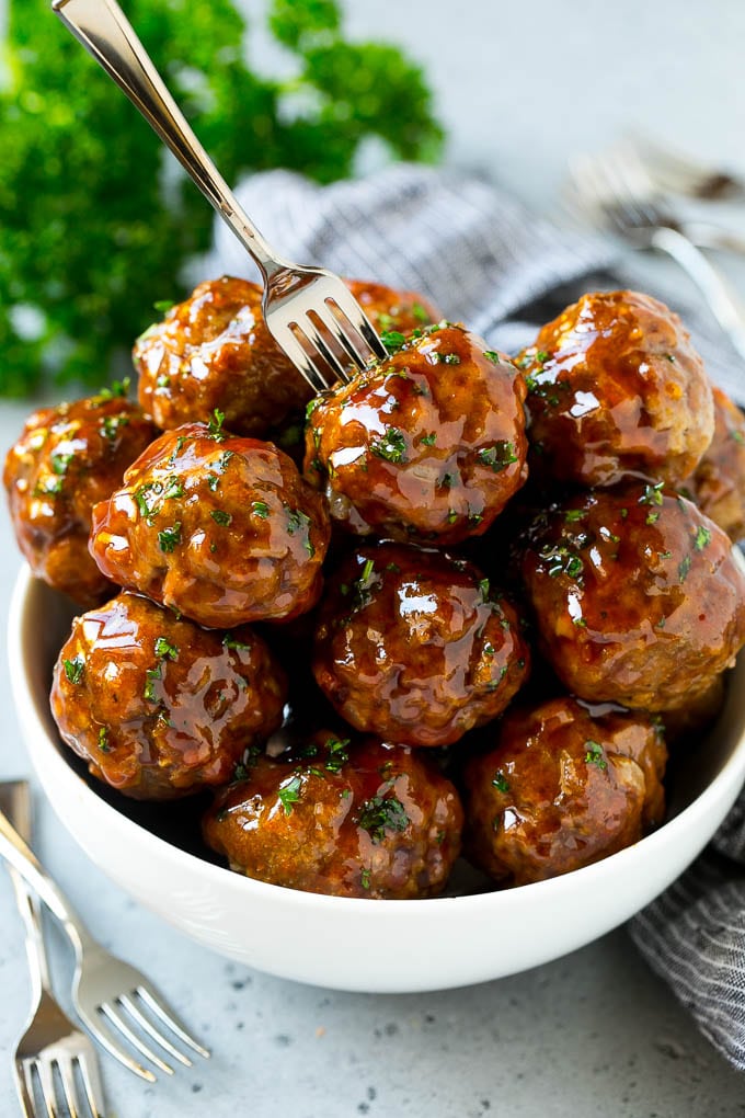 Sweet and Sour Meatballs Recipe | Slow Cooker Meatballs | Crockpot Meatballs | Cocktail Meatballs #meatballs #beef #slowcooker #crockpot #dinner #appetizer #bajap A bowl of sweet and sour meatballs with a cocktail fork in it.