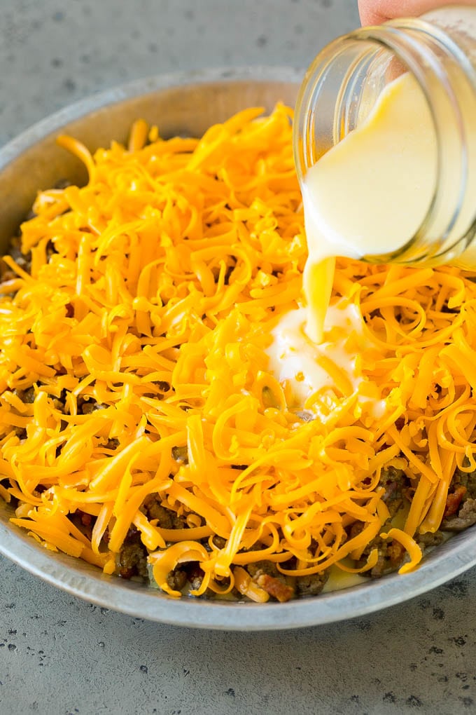 Cheeseburger Pie Recipe | Cheeseburger Casserole | Ground Beef Recipe #cheeseburger #beef #bacon #cheese #casserole #dinner #bajap Egg batter being poured over shredded cheese and ground beef.