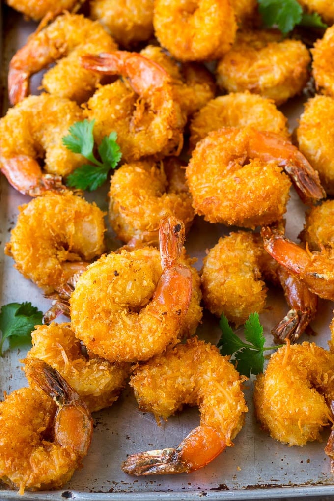 Coconut Shrimp Recipe | Fried Shrimp | Shrimp Appetizer #shrimp #coconut #appetizer #seafood #dinner #bajap A pile of crispy coconut shrimp on a sheet pan with cilantro leaves for garnish.