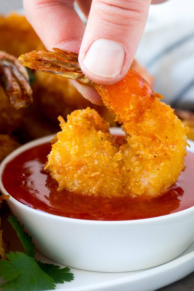 Coconut Shrimp Recipe | Fried Shrimp | Shrimp Appetizer #shrimp #coconut #appetizer #seafood #dinner #bajap A hand dipping a crispy prawn into a bowl of sweet chili sauce.